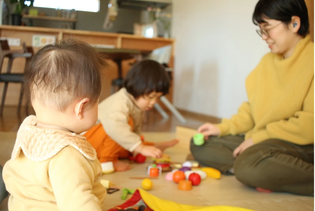 子どもたちが床で遊び、母親が見守っている