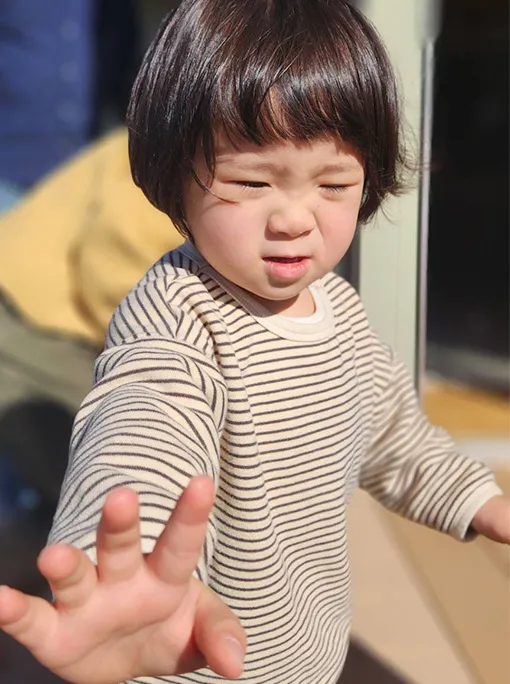 屋外で眩しそうにしている子供の姿